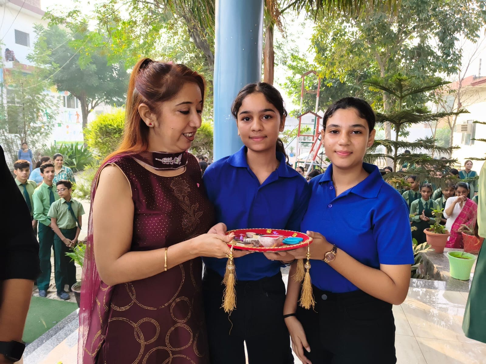 The principal receiving a ceremonial thali from two senior students
