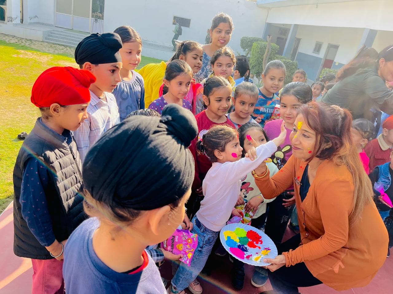 A teacher applying colour to a student's cheek during a Holi celebration