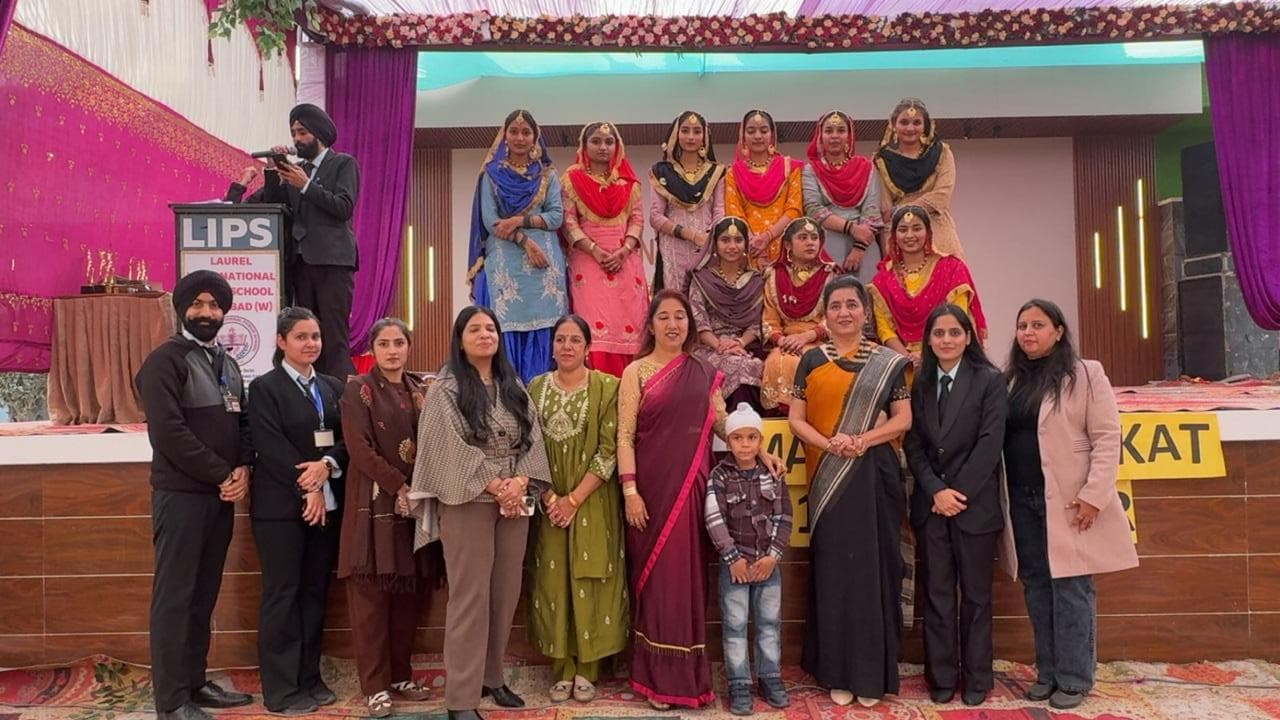 Students in Punjabi folk costume on stage with staff