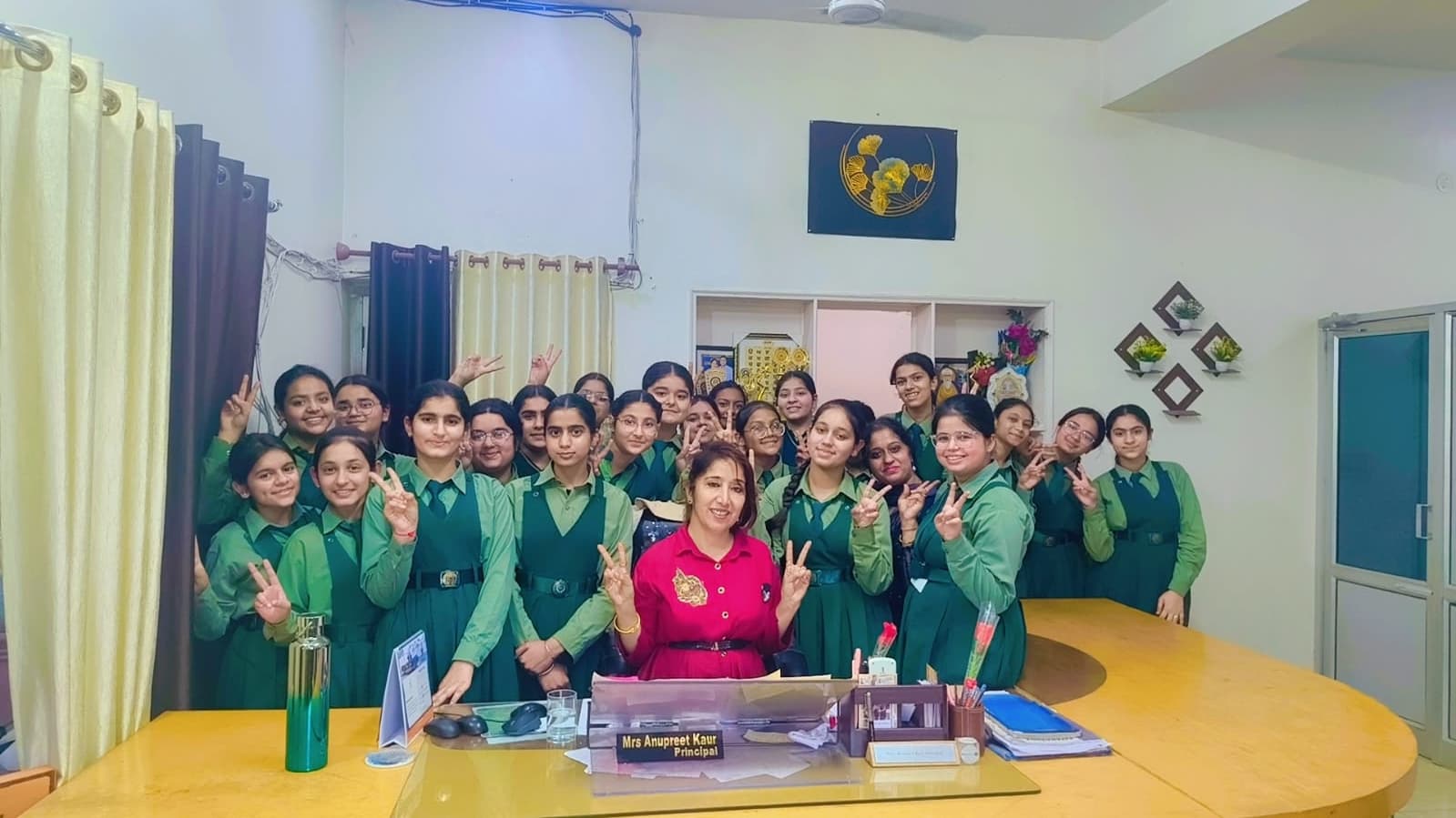 Students in green uniform blazers posing at the reception desk